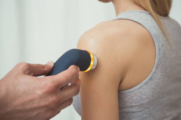 Male physiotherapist performing ultrasound therapy on the shoulder